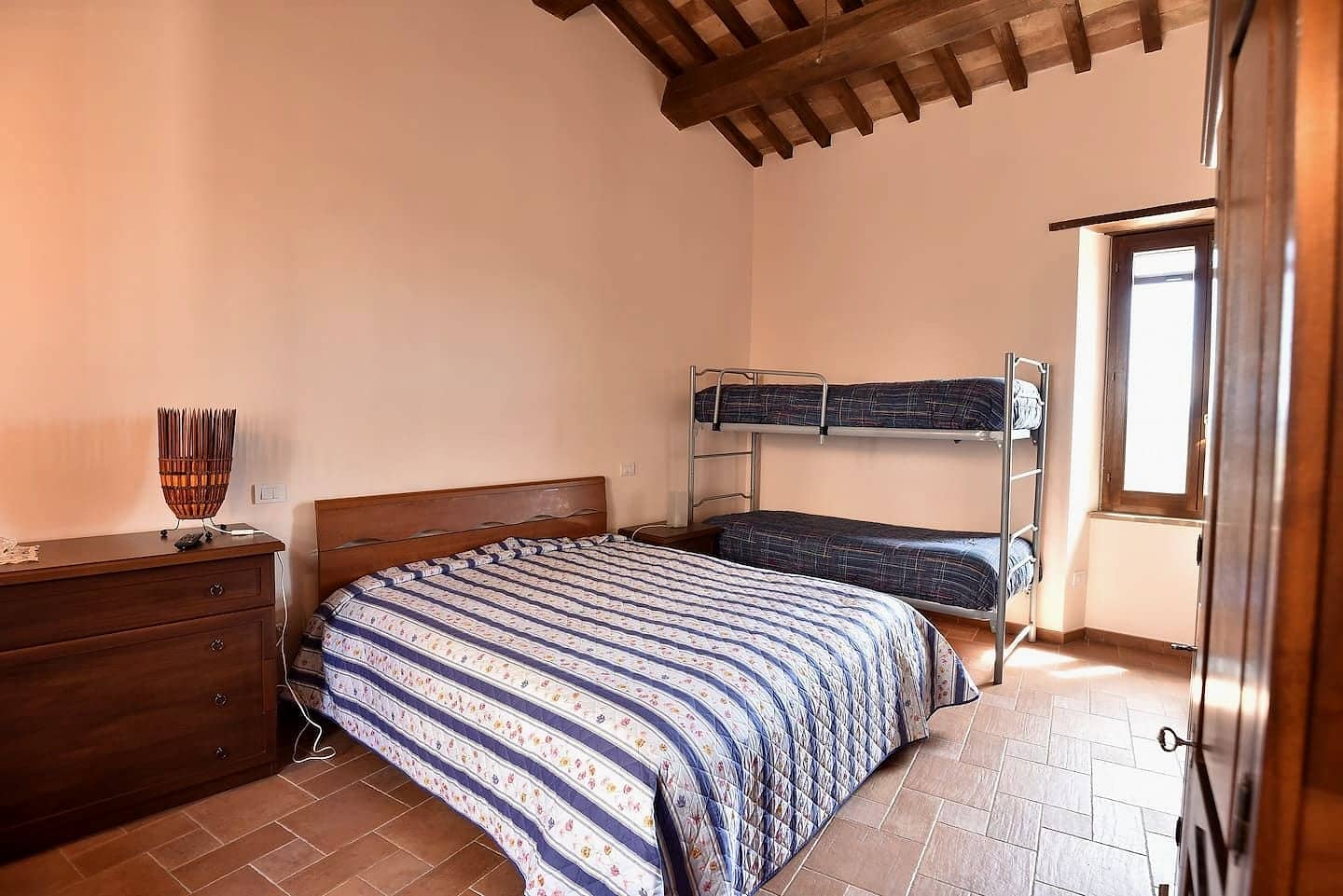 Camera 1: letto matrimoniale e letto a castello sotto un soffitto con travi in legno
