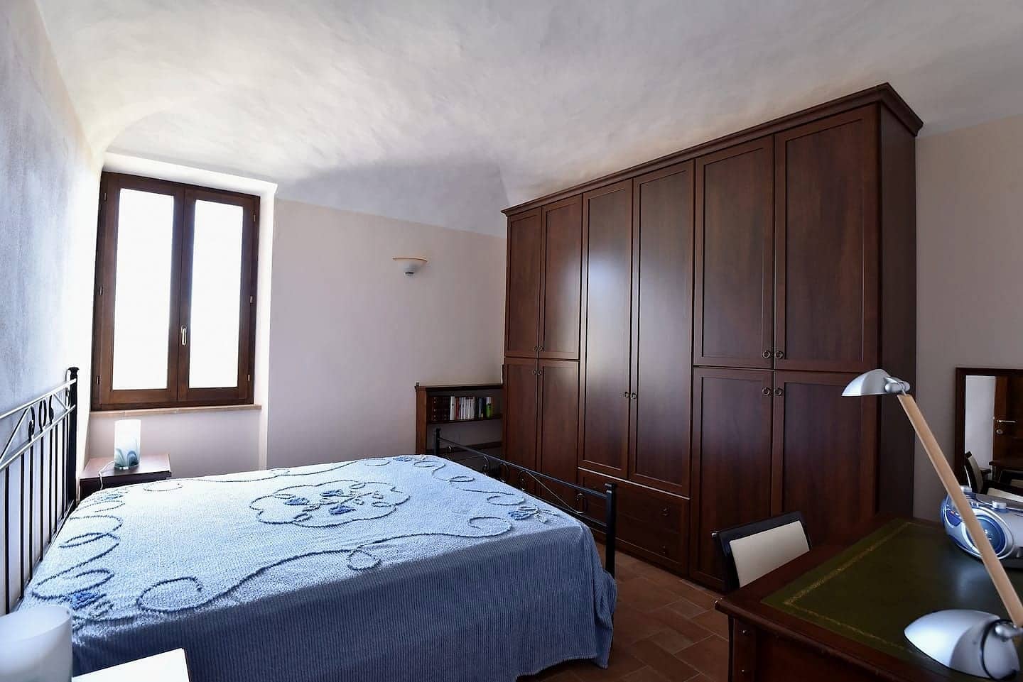 Camera 2: letto matrimoniale con testiera in ferro battuto, grande armadio e finestra sotto una volta a vela