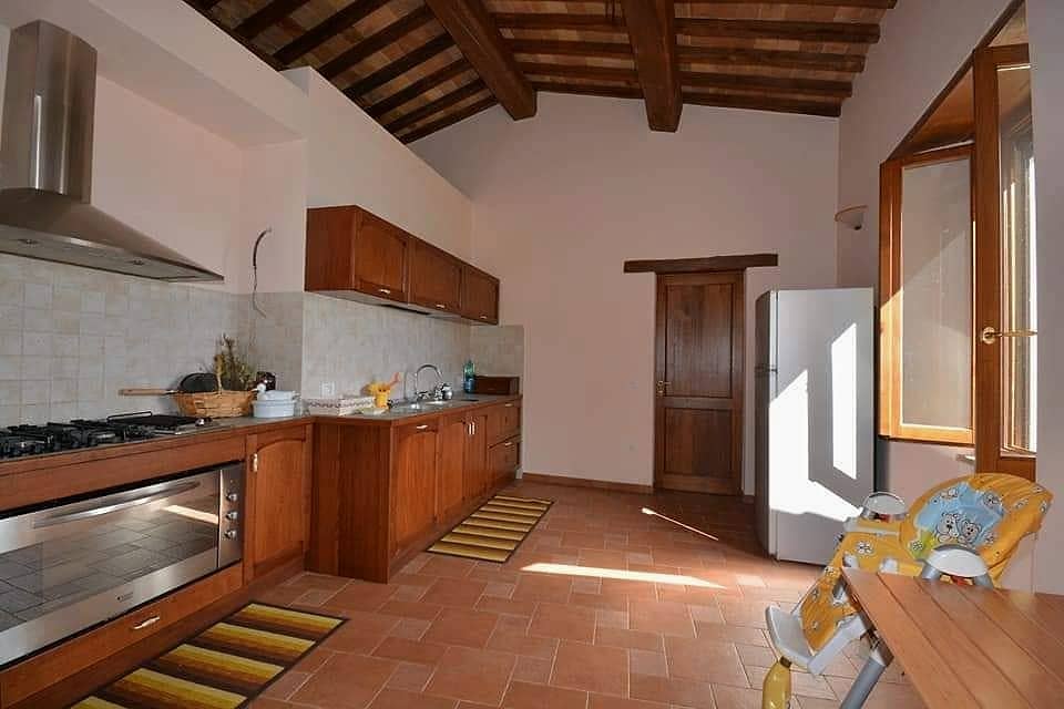 La cucina con piano cottura a gas, grande forno, cappa in acciaio e pavimento in cotto