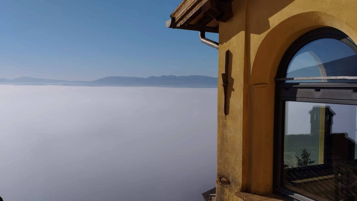 La finestra ad arco della casa affacciata su un mare di nebbia nella Valle Umbra