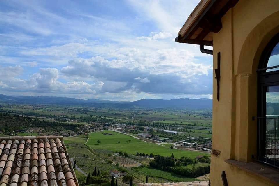 La Valle Umbra vista da una finestra della casa, con i tetti in coppi del borgo in primo piano