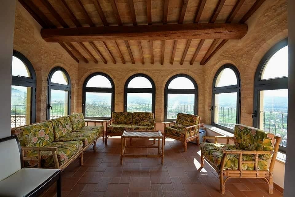 La Loggia: sette finestroni ad arco sulla Valle Umbra, divani in rattan a fiori e soffitto in legno a vista